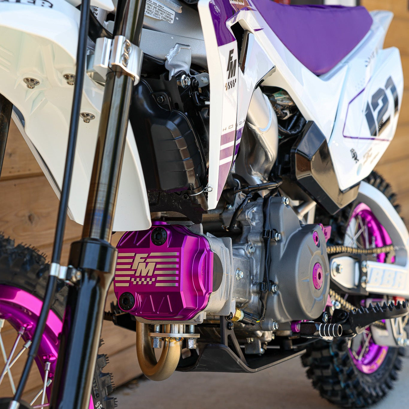 Close-up of a dirt bike with purple and white details on a concrete surface.